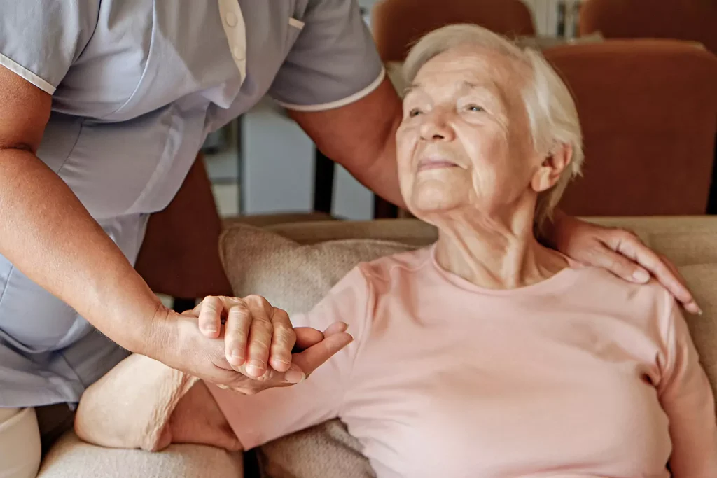 An elderly woman is being supported by her in home nurse